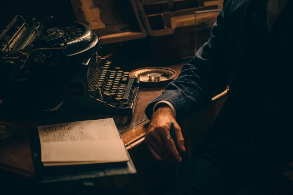 A vintage typewriter and a writer’s hand near a notebook, symbolizing the art of ghostwriting.