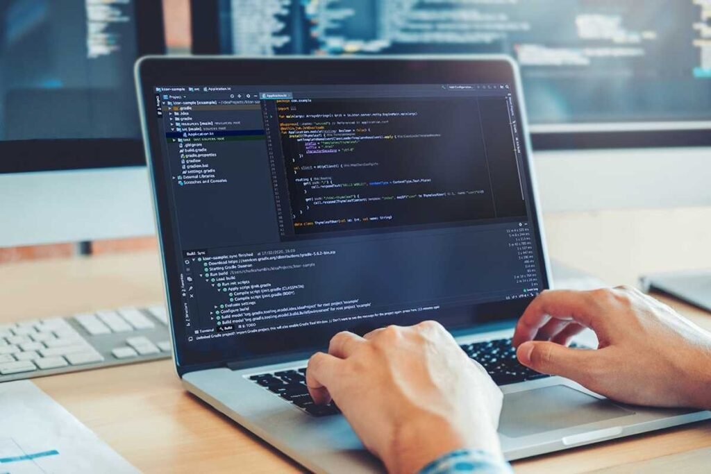 Web developer coding a website on a laptop, with programming code displayed.